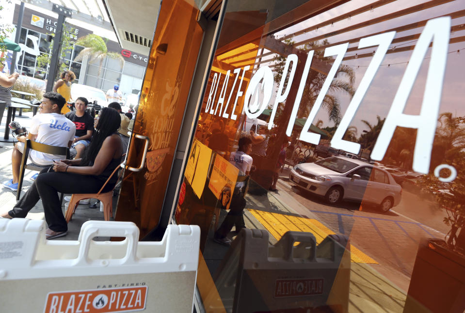 Los Angeles Lakers fans wait in line around noon for promised free pizza that will be handed out between 2 and 5 p.m. at Blaze Pizza, a restaurant chain NBA basketball player LeBron James was an original investor in, Tuesday, July 10, 2018, in Culver City, Calif. James had hinted that he might appear at the location today. (AP Photo/Reed Saxon)