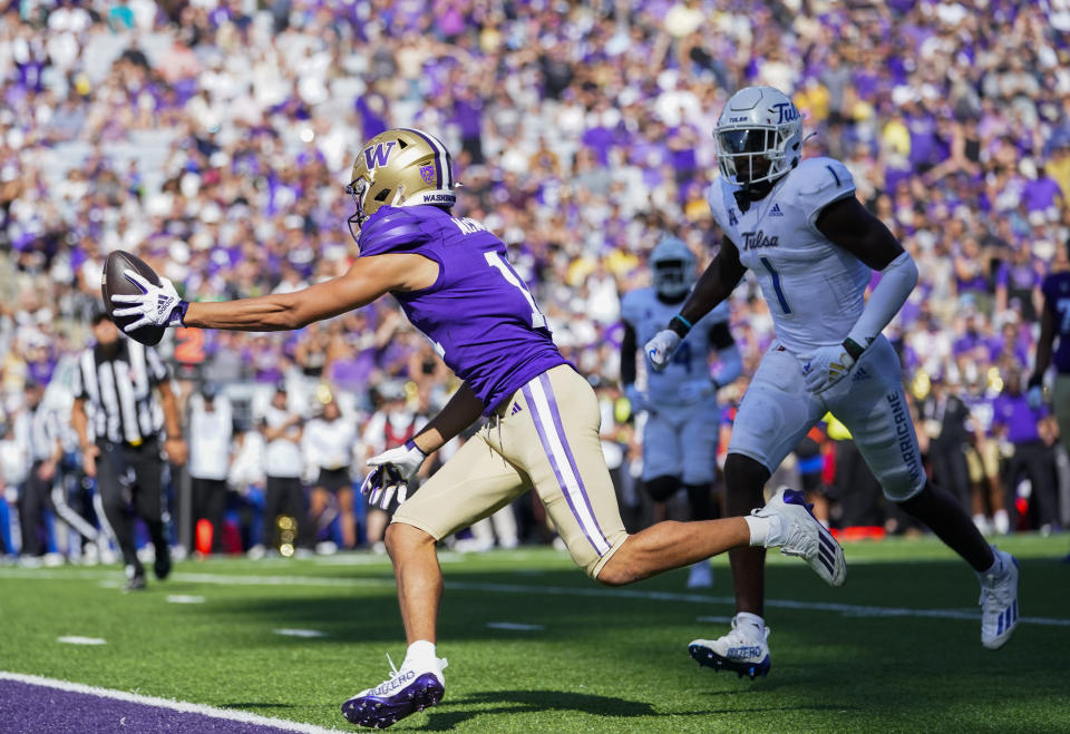 Washington wide receiver Jalen McMillan, left, reaches out to score a touchdown as Tulsa safety Kendarin Ray, right, looks on during the first half of an NCAA college football game Saturday, Sept. 9, 2023, in Seattle. (AP Photo/Lindsey Wasson)