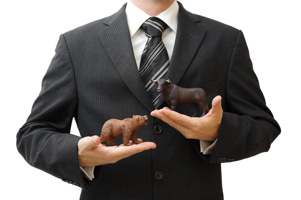 Businessman holding toy bear and bull in his hands