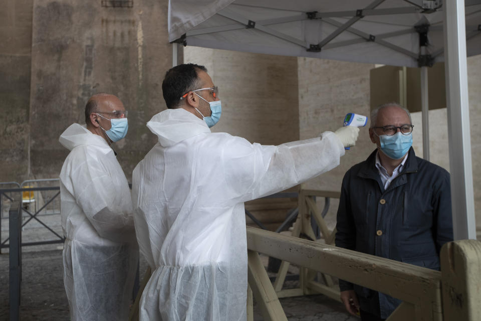 A visitor has his temperature checked in St. Peter's square at the Vatican in the day of the reopening of St. Peter's Basilica, Monday, May 18, 2020. Italy is slowly lifting sanitary restrictions after a two-month coronavirus lockdown. (AP Photo/Alessandra Tarantino)