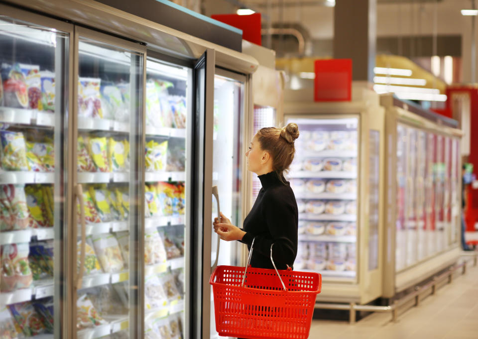 Woman choosing frozen food from a supermarket freezer