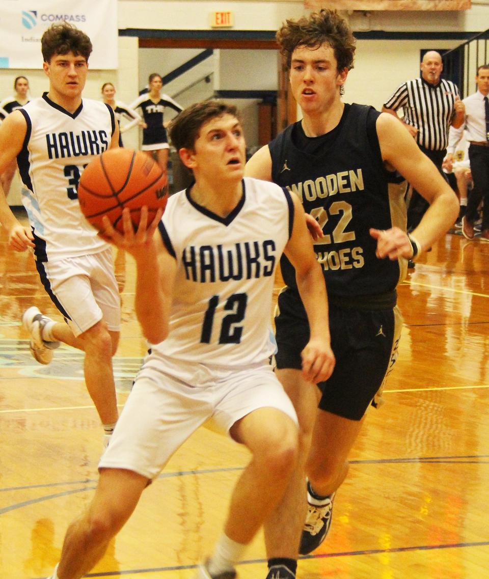 Tyler Curl of Prairie Central attacks the basket as Joey Niebrugge of Teutopolis trails on defense Saturday. Curl led the Hawks with 9 points in their 60-35 loss.