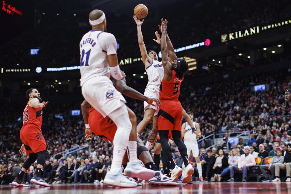 Washington Wizards guard Johnny Davis, center, shoots over Toronto Raptors forward Precious Achiuwa (5) during the first half of an NBA basketball game in Toronto, Sunday, March 26, 2023. (Cole Burston/The Canadian Press via AP)