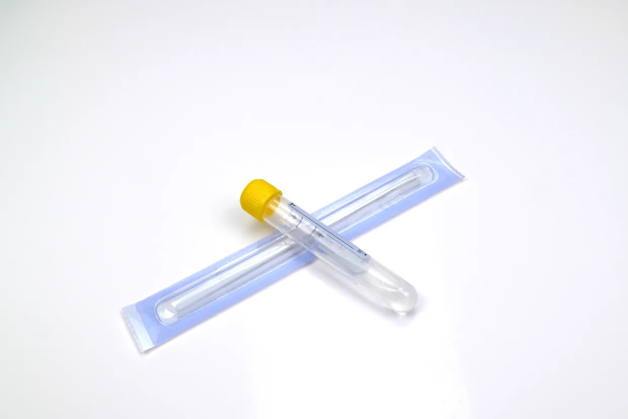 Medical needle and vial on white surface.