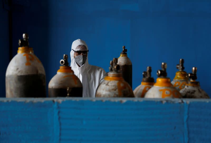 A medical worker stands next to an oxygen cylinder at the Yatharth Hospital in Noida