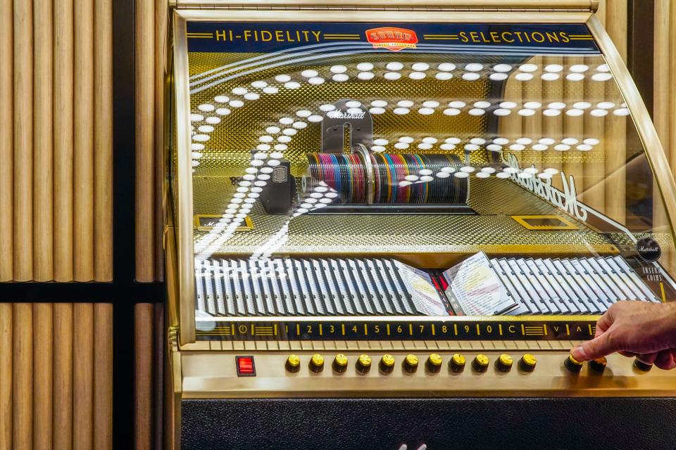 A hand presses a button on a vintage marshall juke box