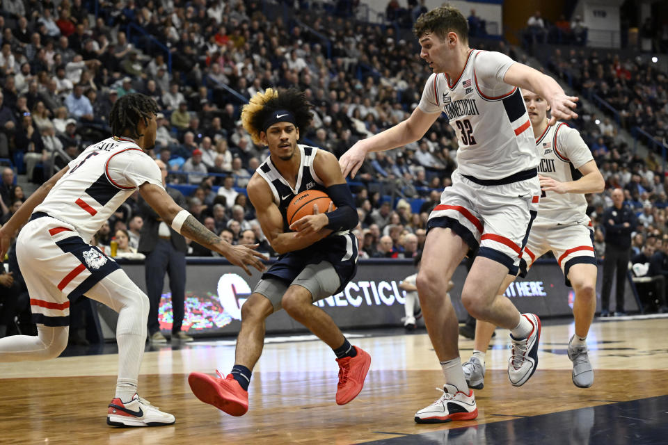 Butler guard DJ Davis, center, moves between the defense of UConn guard Stephon Castle, left, and UConn center Donovan Clingan, right, in the first half of an NCAA college basketball game, Tuesday, Feb. 6, 2024, in Hartford, Conn. (AP Photo/Jessica Hill)