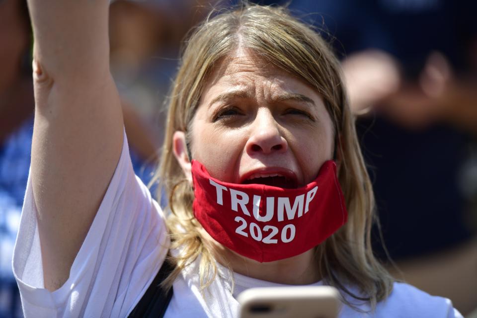 A woman wearing a TRUMP 2020 face mask cheers during a protest rally outside the Pennsylvania Capitol Building regarding the continued closure of businesses due to the coronavirus pandemic on May 15, 2020 in Harrisburg, Pennsylvania.