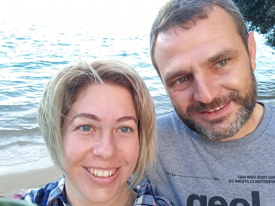 The author and her partner smiling at the camera and standing on a beach.