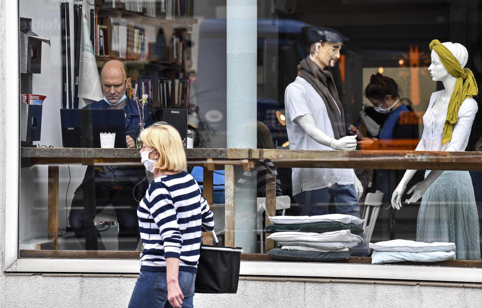 A customer sits with his laptop beside display mannequins at the Cafe Livres in Essen, Germany, Wednesday, May 20, 2020. The cafe set the dolls as placeholders on various places for more distance between customers due to the new coronavirus orders for restaurants and cafes. (AP Photo/Martin Meissner)