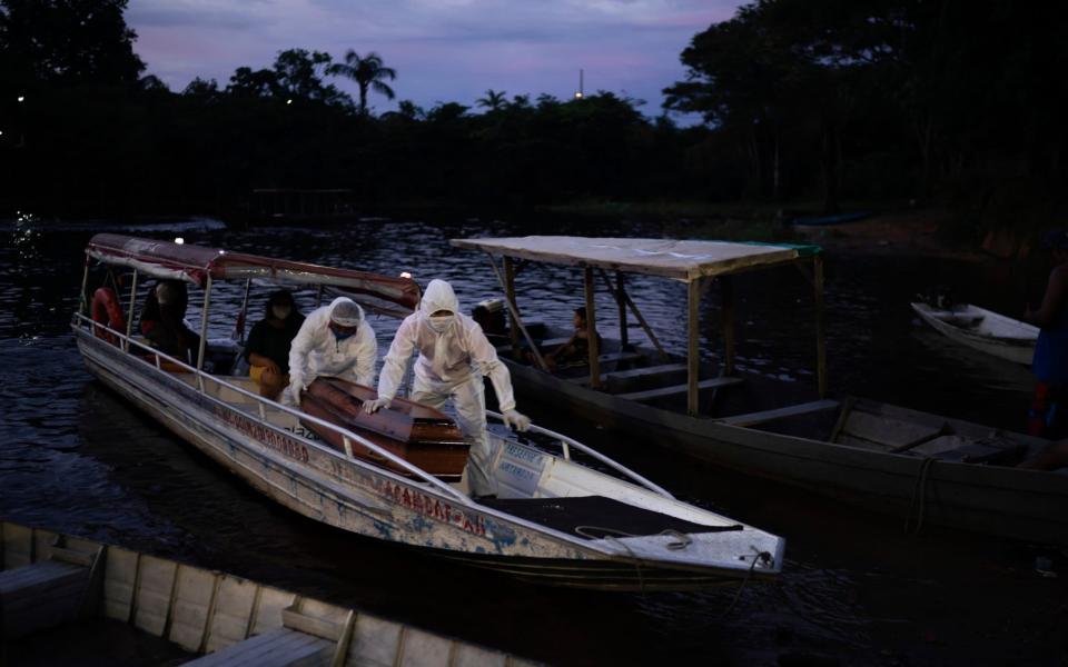 SOS funeral workers transport by boat a coffin carrying the body of an 86-year-old woman suspected to have died of Covid-19, near Manaus, Brazil - AP