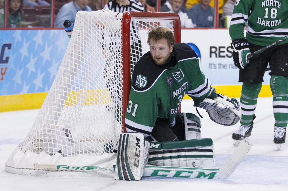 North Dakota's Zane Gothberg looks for the puck after having his masked knocked off during the second period of an NCAA men's college hockey Frozen Four tournament game against Minnesota, Thursday, April 10, 2014, in Philadelphia. (AP Photo/Chris Szagola)