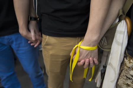 Student protesters hold hands wearing a yellow ribbon, a symbol of the "Occupy Central" movement, as they gather around the Golden Bauhinia Square during an official flag raising ceremony to commemorate Chinese National Day in Hong Kong October 1, 2014. REUTERS/Tyrone Siu