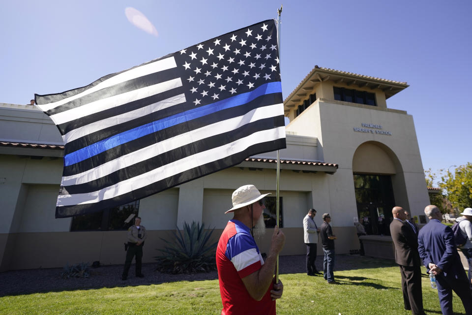 A supporter waves a flag outside of the Palmdale Sheriff's Station during a press to announce an arrest in the ambush killing of a Los Angeles County sheriff's deputy Monday, Sept. 18, 2023, in Palmdale, Calif. Deputy Ryan Clinkunbroomer was shot and killed while sitting in his patrol car Saturday evening in Palmdale.(AP Photo/Marcio Jose Sanchez)