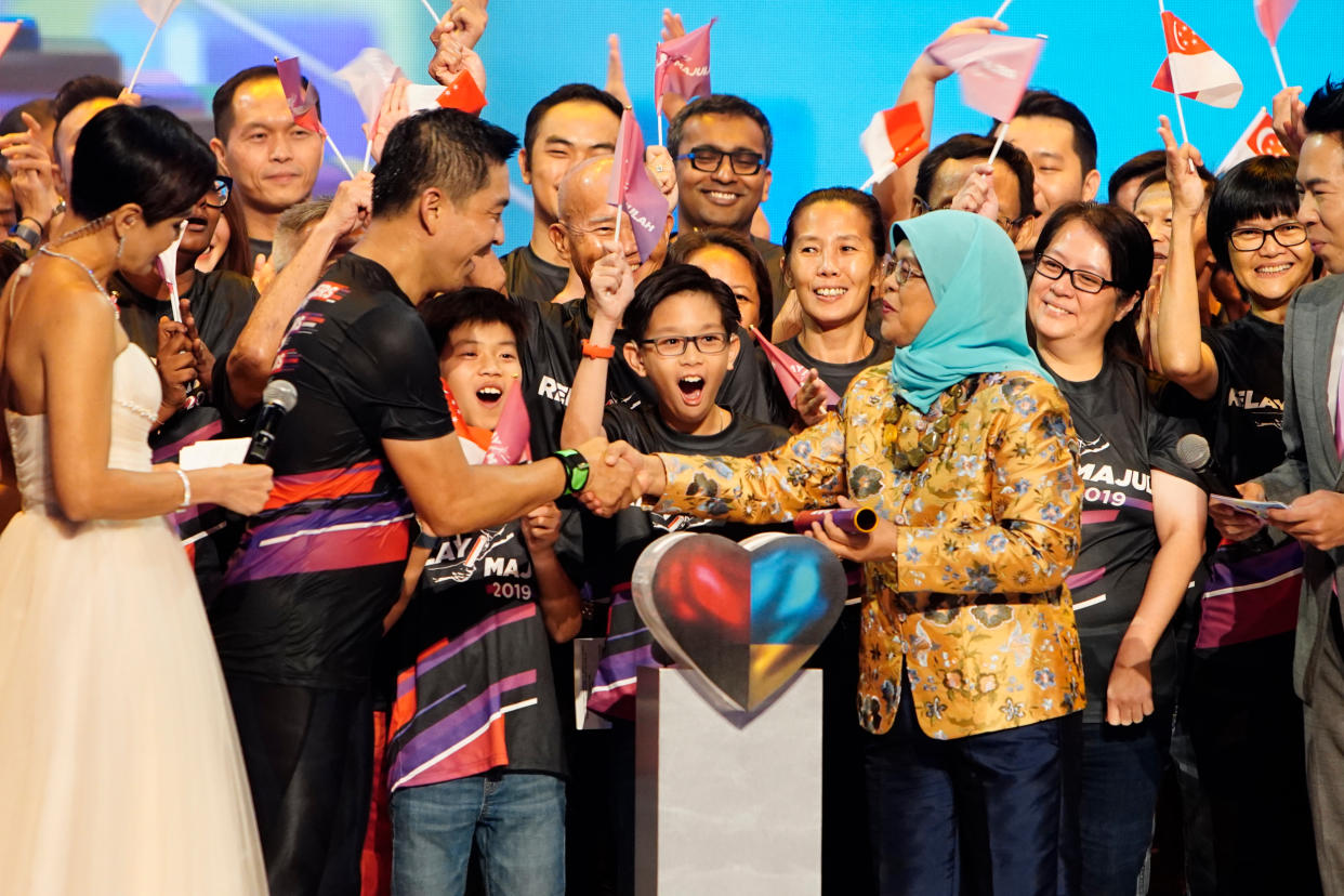 Speak of Parliament and relay runner Tan Chuan-Jin hands the baton of the Relay Majulah charity initiative to President Halimah Yacob. (PHOTO: Relay Majulah)                               