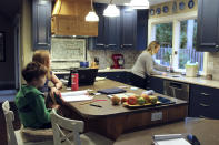 Charlie Dale, left, works on his math notebook with help from his older sister Maddi Dale as their mother cooks pancakes in their home in Lake Oswego, Ore., Oct. 30, 2020. The children have been learning remotely since March. In Oregon, one of only a handful of states that has required a partial or statewide closure of schools in the midst of the COVID-19 pandemic, parents in favor of their children returning to in-person learning have voiced their concerns and grievances using social media, petitions, letters to state officials, emotional testimonies at virtual school board meetings and on the steps of the state's Capitol. (AP Photo/Sara Cline)