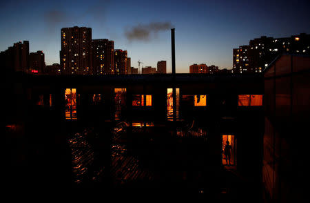 FILE PHOTO: A female migrant construction worker walks into her dormitory near newly-built residential apartments in Shanghai August 12, 2013. REUTERS/Aly Song/File Photo