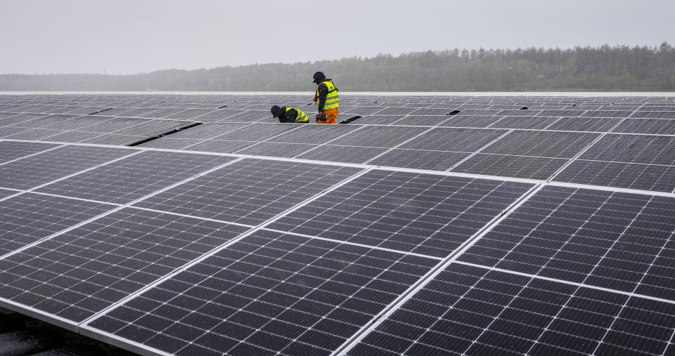Solar panels are installed at a floating photovoltaic plant on a lake in Haltern, Germany, Friday, April 1, 2022. Once completed, around 5,800 photovoltaic modules will produce around 3 million kilowatt hours of electricity per year, saving 1,100 tons of CO2 to fight climate change with renewable power instead of oil, gas and coal. (AP Photo/Martin Meissner)