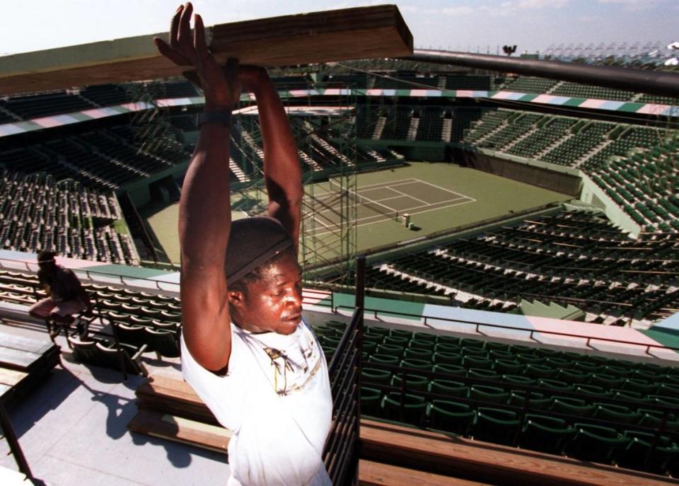 In 1994, David Mathew carries a plank used for the bleachers on the top level of the stadium at the Lipton Tennis site. Workers were busy preparing near Key Biscayne.