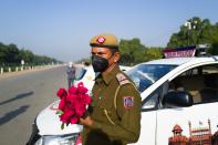 A policeman holds a bunch of roses to distribute to people in a bid to inspire them to stay home during a one-day Janata (civil) curfew imposed as a preventive measure against the COVID-19 coronavirus in New Delhi on March 22, 2020. - Nearly one billion people around the world were confined to their homes, as the coronavirus death toll crossed 13,000 and factories were shut in worst-hit Italy after another single-day fatalities record. (Photo by Jewel SAMAD / AFP) (Photo by JEWEL SAMAD/AFP via Getty Images)