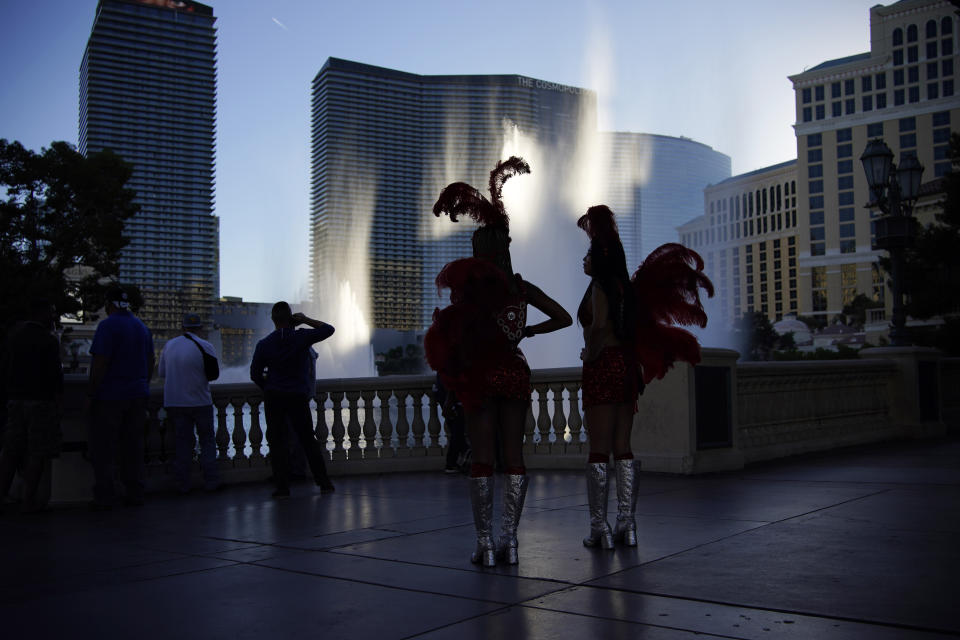 People dressed as showgirls stand along the Las Vegas Strip, Thursday, Nov. 19, 2020, in Las Vegas. As the coronavirus surges to record levels in Nevada, the governor has implored residents to stay home. But Democrat Steve Sisolak has also encouraged out-of-state visitors, the lifeblood of Nevada's limping economy, to come to his state and spend money in Las Vegas. (AP Photo/John Locher)