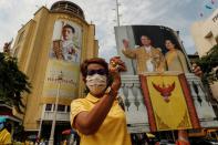 A royalist holds a picture of Thailand's late King Bhumibol Adulyadej and Queen Mother Sirikit in front of an image of King Maha Vajiralongkorn in Bangkok, Thailand