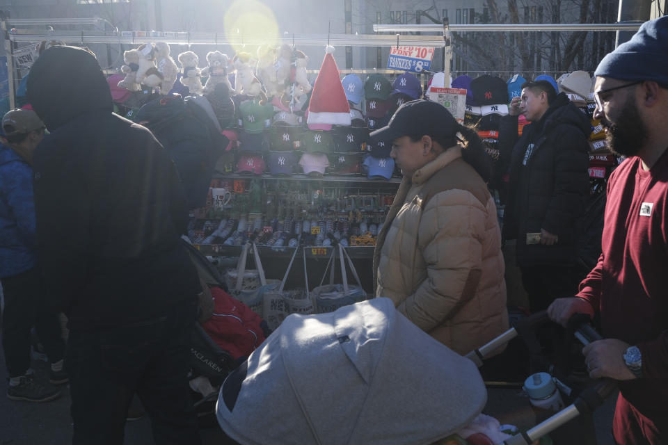 Pedestrians pass by vendors on the Brooklyn Bridge in New York, Tuesday, Jan. 2, 2024. New York City will ban vendors from the Brooklyn Bridge starting Wednesday, Jan. 3, 2024. The move is intended to ease overcrowding on the famed East River crossing, where dozens of souvenir sellers currently compete for space with tourists and city commuters. (AP Photo/Seth Wenig)