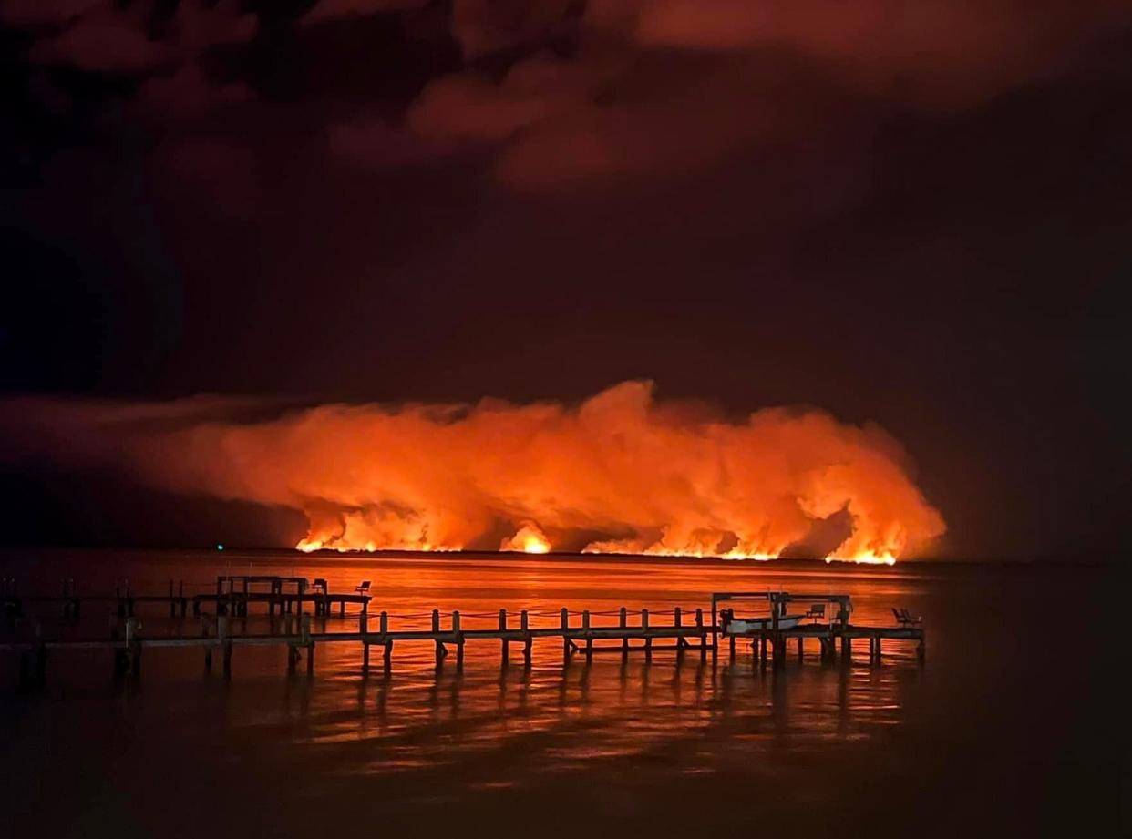 In this photo taken late Saturday from Shiloh's Steak and Seafood restaurant in Titusville, a brush fire burns in the Peacocks Pocket section of the Merritt Island National Wildlife Refuge after a lightning strike.