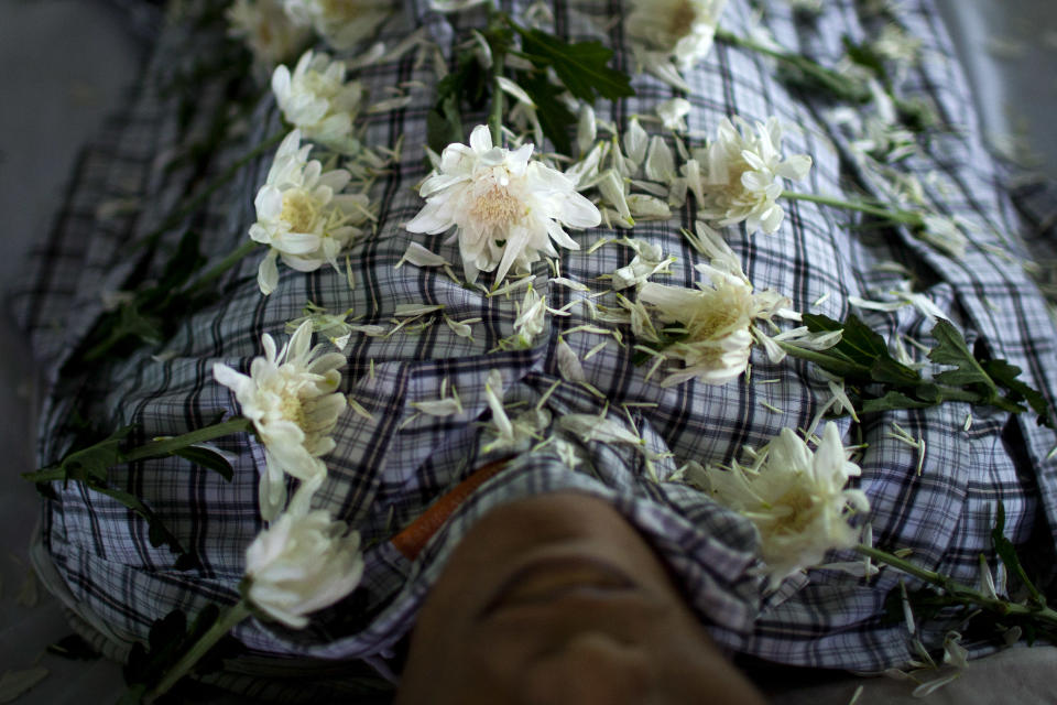 In this Sept. 4, 2012 photo, white chrysanthemum flowers are arranged on the body of HIV victim Kyaw Naing Aung, who died a day earlier at the age of 29, during his funeral on the outskirts of Yangon, Myanmar. Myanmar ranks among the world's hardest places to get HIV care, and health experts warn it will take years to prop up a broken health system hobbled by decades of neglect. (AP Photo/Alexander F. Yuan)