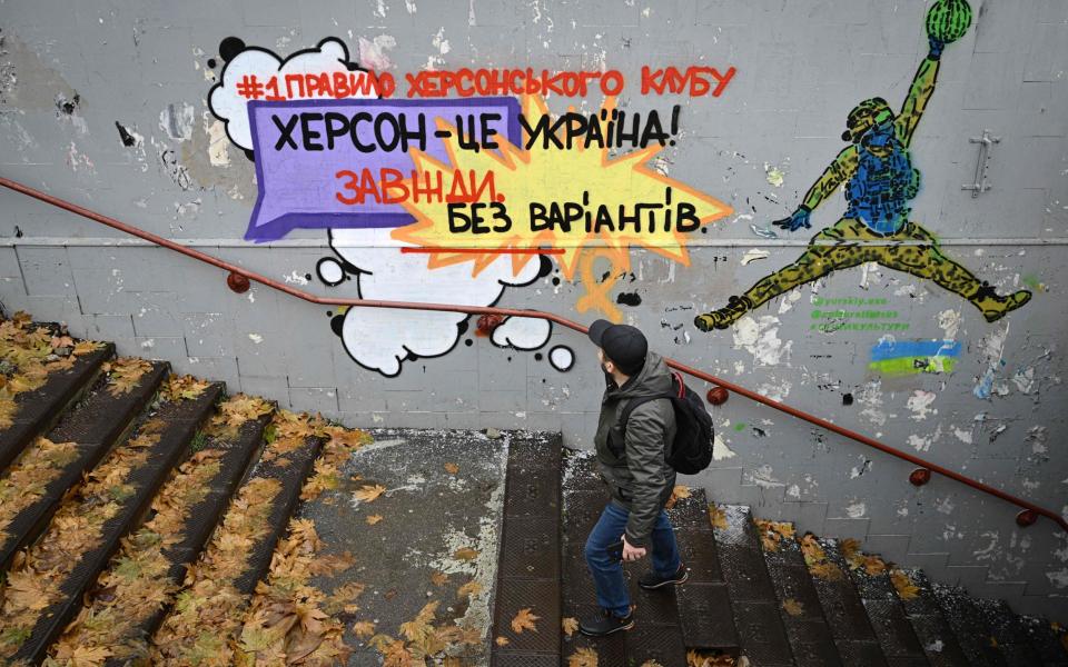 A man walks past a graffiti reading "First rule of Khersons club: Kherson is Ukraine! Always, without options" - GENYA SAVILOV/AFP via Getty Images