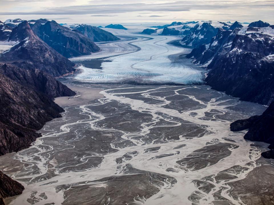 melting glacier in valley between mountains aerial view