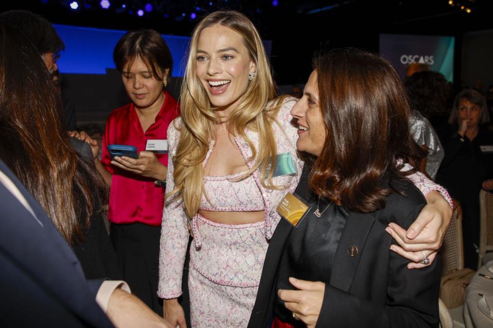 Two smiling women embrace.