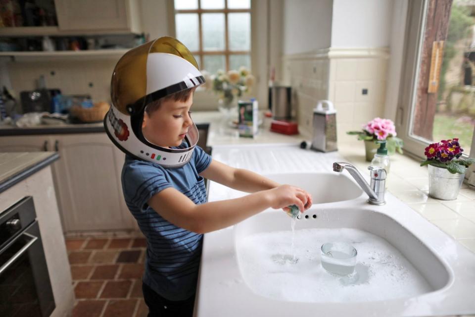 An image of a boy doing dishes.