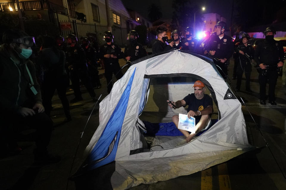 A demonstrator sets up a tent in front of police in the Echo Park section of Los Angeles Thursday, March 25, 2021. Demonstrators gathered Wednesday night to protest the planned temporary closure of a Los Angeles park that would displace a large homeless encampment, which has grown throughout the coronavirus pandemic. (AP Photo/Marcio Jose Sanchez)