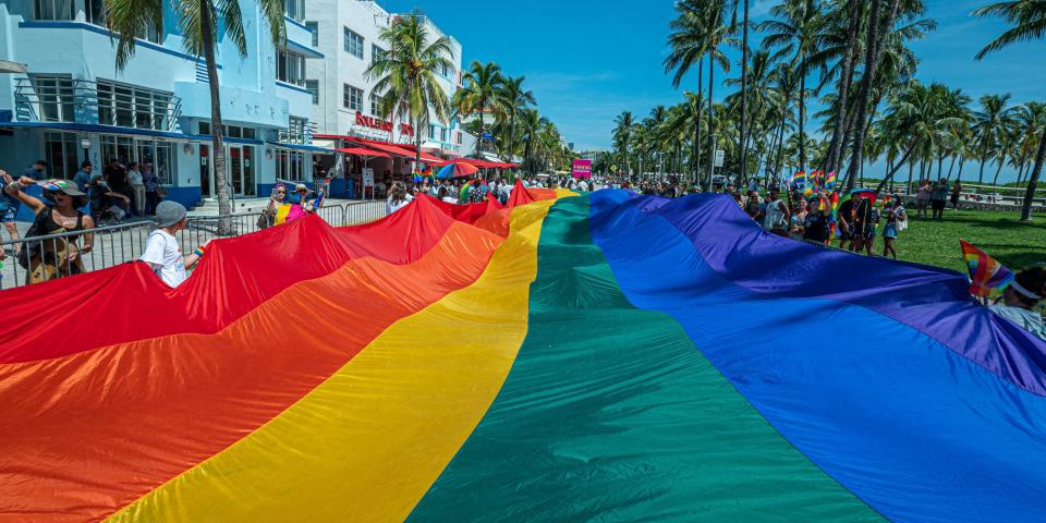 A huge multi-colored flag flies over Ocean Drive as people participate in the Pride Parade, during the Miami Beach Pride Festival, in Lummus Park, South Beach, Florida on September 19, 2021.