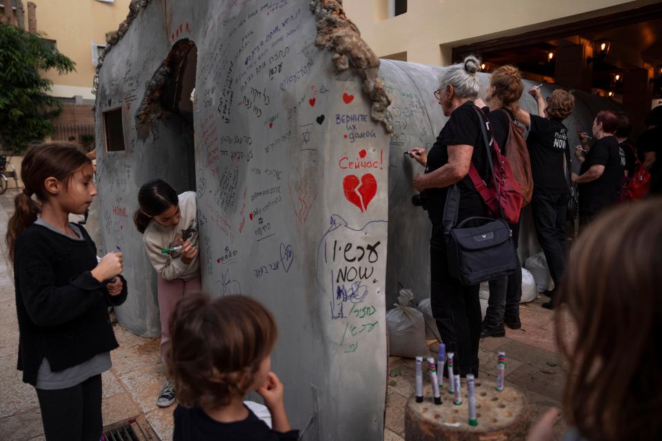 People write on an installation simulating a tunnel in Gaza in an act of solidarity with hostages believed to be held underground by Hamas in Tel Aviv on Nov. 22, 2023.