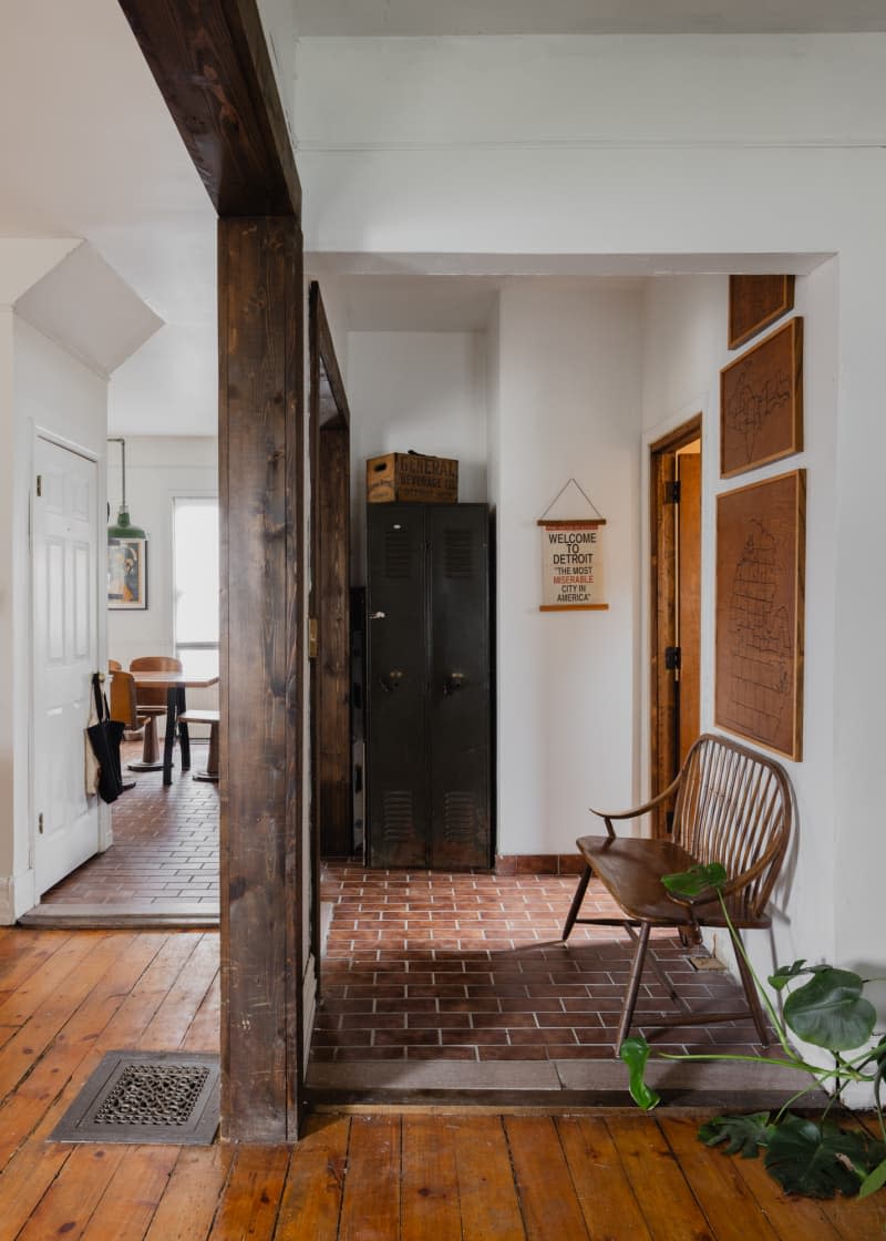 Hallway with brick-like and wood flooring, wood trim, and wooden bench.