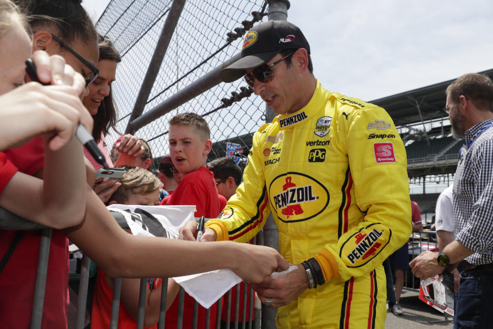 Helio Castroneves, of Brazil, signs autographs for fans during practice for the Indianapolis 500 IndyCar auto race at Indianapolis Motor Speedway, Thursday, May 16, 2019 in Indianapolis. (AP Photo/Michael Conroy)