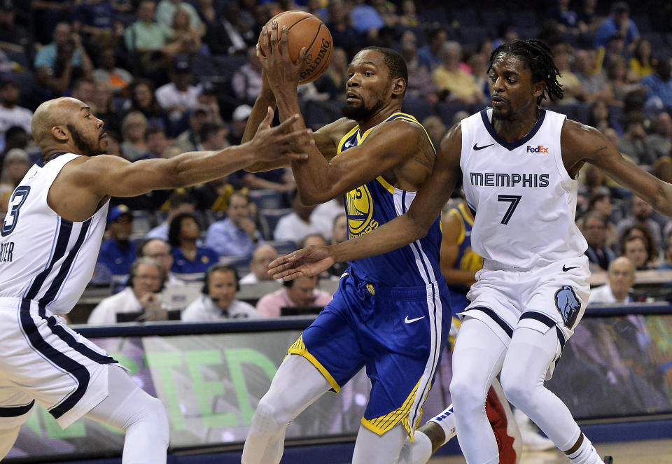 Golden State Warriors forward Kevin Durant (35) drives between Memphis Grizzlies guard Jevon Carter (3) and forward Justin Holiday (7) during the first half of an NBA basketball game Wednesday, April 10, 2019, in Memphis, Tenn. (AP Photo/Brandon Dill)