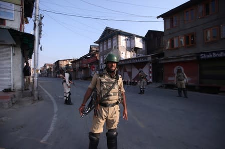 Indian security personnel stand guard on a deserted road during restrictions after scrapping of the special constitutional status for Kashmir by the Indian government, in Srinagar