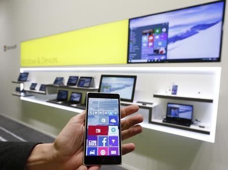 A Microsoft representative holds a Windows smartphone with Windows 10 operating system in front of other devices with Windows 10 at the CeBIT trade fair in Hanover March 14, 2015. REUTERS/Morris Mac Matzen