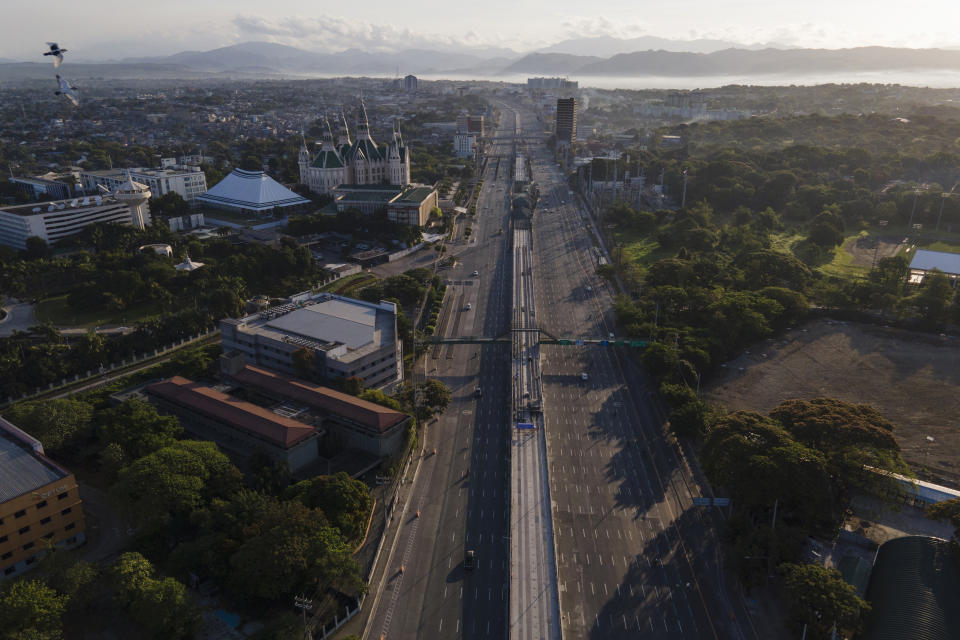 Mountain ranges can be seen behind an almost empty Commonwealth Avenue as the government implements a strict lockdown to prevent the spread of the coronavirus on Good Friday, April 2, 2021 in Quezon city, Philippines. Filipinos marked Jesus Christ's crucifixion Friday in one of the most solemn holidays in Asia's largest Catholic nation which combined with a weeklong coronavirus lockdown to empty Manila's streets of crowds and heavy traffic jams. Major highways and roads were eerily quiet on Good Friday and churches were deserted too after religious gatherings were prohibited in metropolitan Manila and four outlying provinces. (AP Photo/Aaron Favila)
