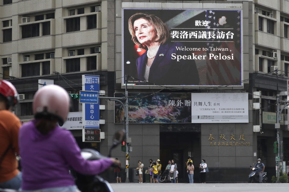 People walk past a billboard welcoming U.S. House Speaker Nancy Pelosi, in Taipei, Taiwan, Wednesday, Aug 3, 2022. Pelosi arrived in Taiwan late Tuesday, becoming the highest-ranking American official in 25 years to visit the self-ruled island claimed by China, which quickly announced that it would conduct military maneuvers in retaliation for her presence. (AP Photo/Chiang Ying-ying)