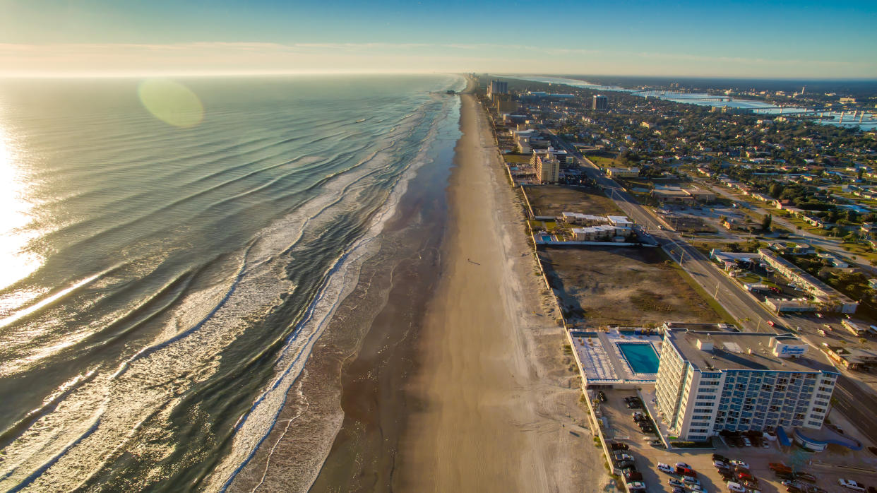 An aerial shot shows Dayton Beach in Daytona, Florida from above during a dramatic sunrise.