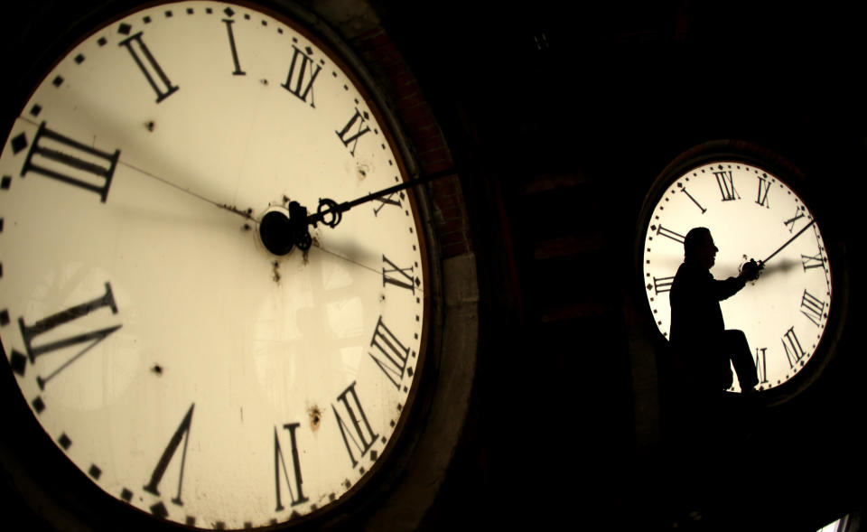 FILE - Custodian Ray Keen inspects a clock face before changing the time on the 100-year-old clock atop the Clay County Courthouse Saturday, March 8, 2014, in Clay Center, Kan. For the first time in history, world timekeepers may have to consider subtracting a second from our clocks in a few years because the planet is rotating a tad faster. (AP Photo/Charlie Riedel, File)