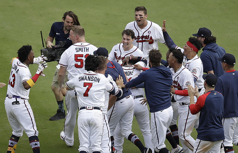 Atlanta Braves' Max Fried, center, is mobbed after making the winning hit against the Miami Marlins during the 10th inning of a baseball game Sunday, July 4, 2021, in Atlanta. (AP Photo/Ben Margot)