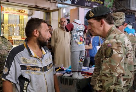 Major General Rupert Jones, the British deputy commander of the international coalition fighting Islamic State, talks to a market trader in East Mosul, Iraq June 21, 2017, where businesses have re-opened after Islamic State was pushed out of the eastern part of Iraq's second largest city where Iraqi security forces are still fighting to liberate the Western side. REUTERS/Marius Bosch