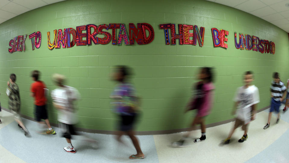 In this photo taken Friday, Sept. 6, 2013, walk between classes past a sign extolling a leadership principle at Indian Trails Elementary school in Independence, Mo. The school is one of 1,400 nationwide utilizing a program called "The Leader in Me" which is based on the late self-help guru Stephen Covey's best-selling "The Seven Habits of Highly Effective People." (AP Photo/Charlie Riedel)