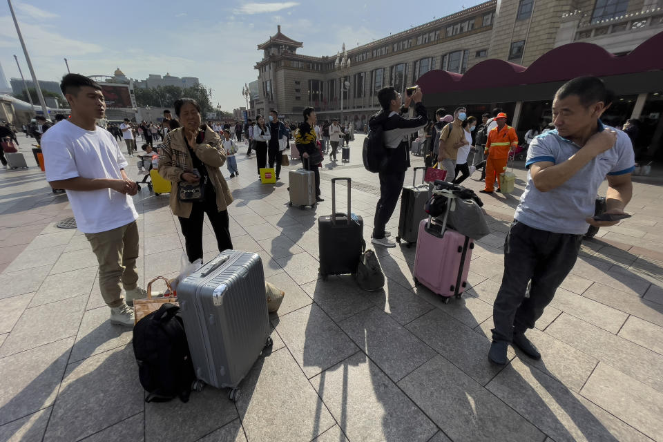 Travelers with their luggage wait at a square in Beijing Railway Station in Beijing, Friday, Sept. 29, 2023. Tens of millions of Chinese tourists are expected to travel within their country, splurging on hotels, tours, attractions and meals in a boost to the economy during the 8-day autumn holiday period that began Friday. (AP Photo/Andy Wong)