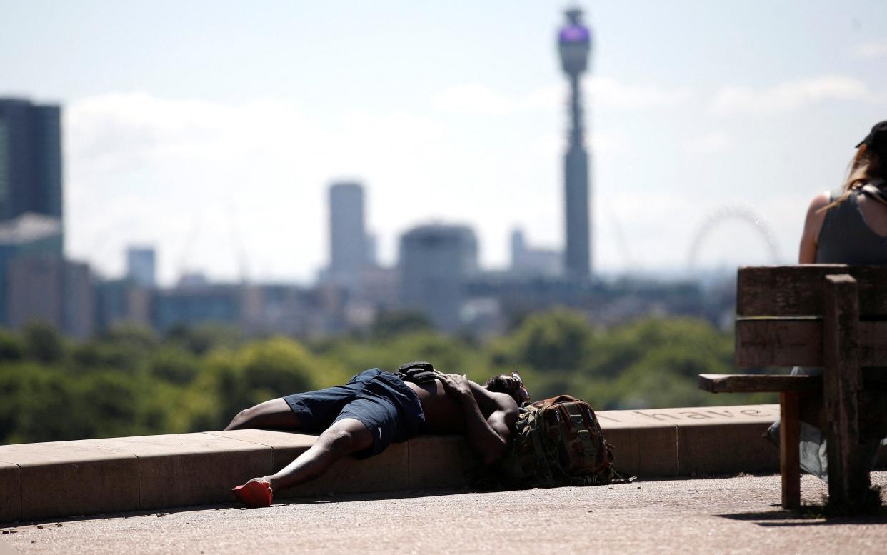 A man lies in the sun at Primrose Hill, in London, Britain - Peter Nicholls/REUTERS